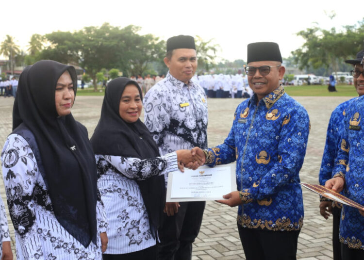 Sekda Aceh Utara, Dr. A. Murtala, M.Si, menyerahkan penghargaan kepada guru berprestasi pada upacara peringatan Hardikda ke-66 di lapangan upacara Kantor Bupati Aceh Utara, Lhoksukon