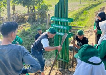 Mahasiswa KKN-PPM Unimal Kelompok 44 merampungkan pemasangan gapura di Desa Keude Geudong, Aceh Utara