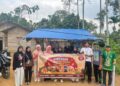Mahasiswa KKN Kelompok 39 Unimal memasang spanduk promosi UMKM warga di Desa Sido Muliyo, Kutamakmur, Aceh Utara