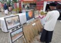 Pengunjung mengamati deretan foto dokumentasi banjir di Kecamatan Langkahan yang dipamerkan dalam rangkaian peringatan HUT ke-800 Aceh Utara/Samudra Pasai