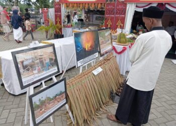 Pengunjung mengamati deretan foto dokumentasi banjir di Kecamatan Langkahan yang dipamerkan dalam rangkaian peringatan HUT ke-800 Aceh Utara/Samudra Pasai